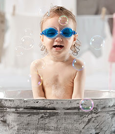 Chłopiec w niebieskich okularach pływackich w trakcie kąpieli z bąbelkami