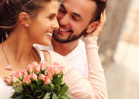 Uśmiechnięta kobieta trzyma w dłoniach bukiet kwiatów, który dostałą od mężczyzny