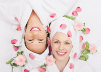 Dwie uśmiechnięte dziewczyny w białych ręcznikach na głowach w czasie zabiegów spa