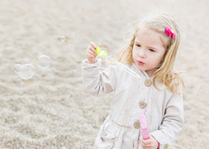 Dziewczynka na plaży puszcza bańki mydlane
