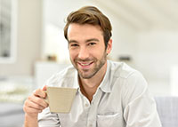 Uśmiechnięty mężczyzna Trzymający kubek z kawą