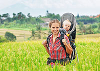 Uśmiechnięta kobieta z dzieckie w nosidełku w trakcie wycieczki