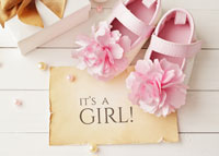 Różowe buciki i kartka z napisem: it's a girl