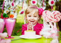 Radosna dziewczynka na imprezie urodzinowj dmucha świeczki na torcie