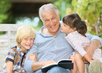 Uśmiechnięty dziadek czytający książkę dwójce wnucząt
