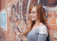 Dziewczyna oparta o ścianę czytająca SMS'a