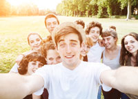 Młody mężczyzna robi selfie z grupą przyjaciół