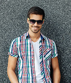 Przystojny, młody mężczyzna w okularach przeciwsłonecznych i kraciastej koszuli