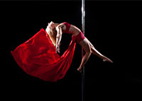 Kobieta w czerwonej sukni ćwicząca pole dance
