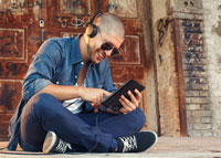 Uśmiechnięty mężczyzna w słuchawkach na głowie słuchający muzyki z telefonu