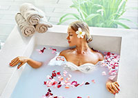 Kobieta w trakcie aromaterapeutycznej kąpieli z płatkami kwiatów