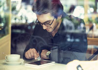 Przystojny mężczyzna z tabletem w trakcie porannej kawy w restauracji